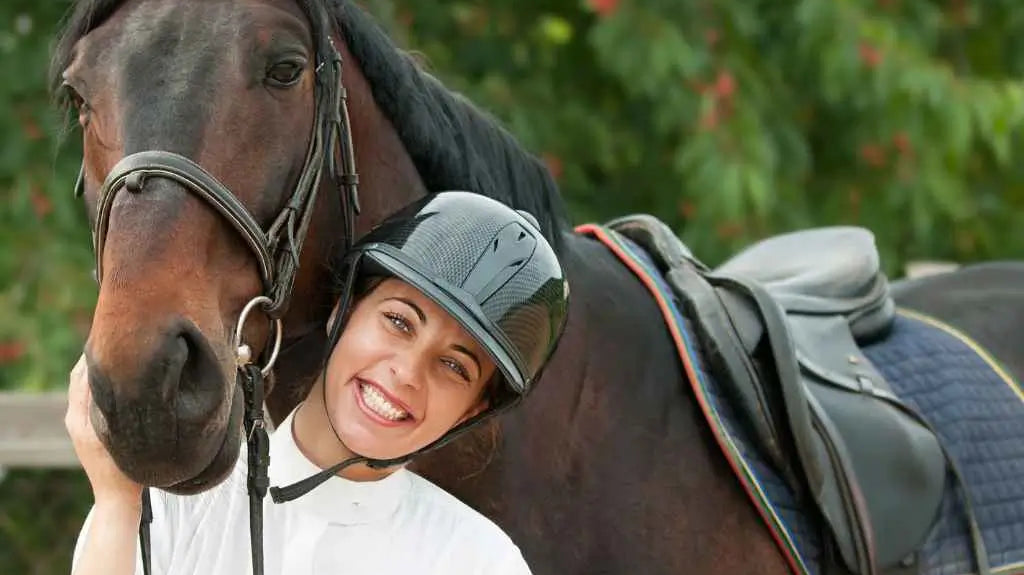 Woman standing under horses head - just horse riders