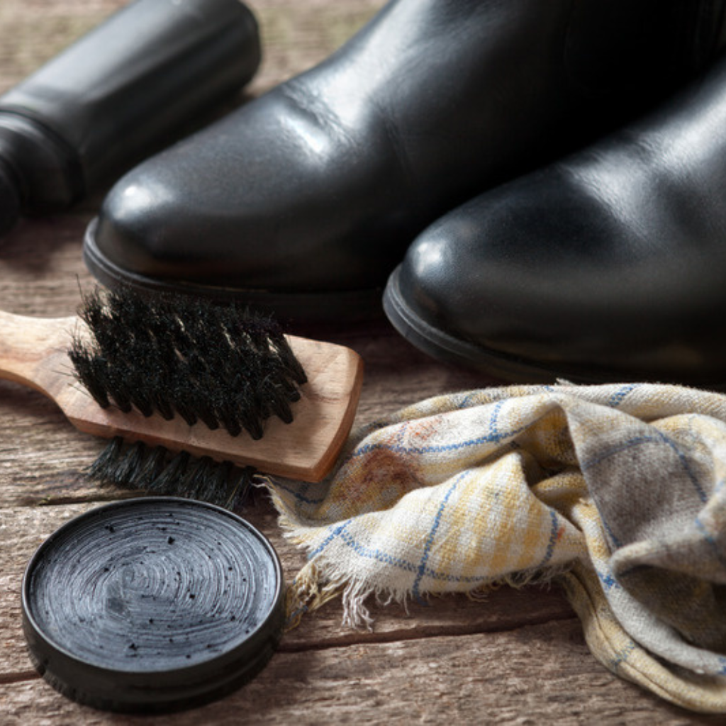 Boot polish, brush and cloth with black leather boots