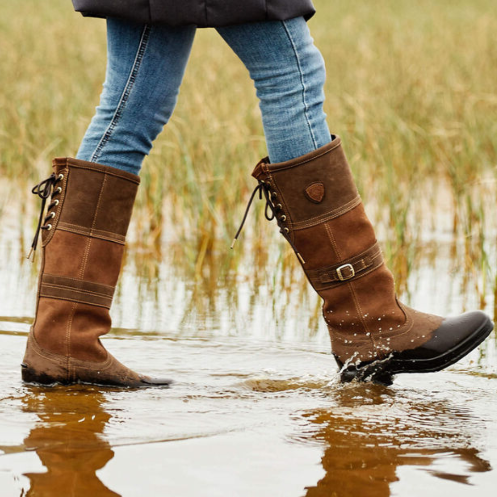Brown lace-up country boots splashing through water