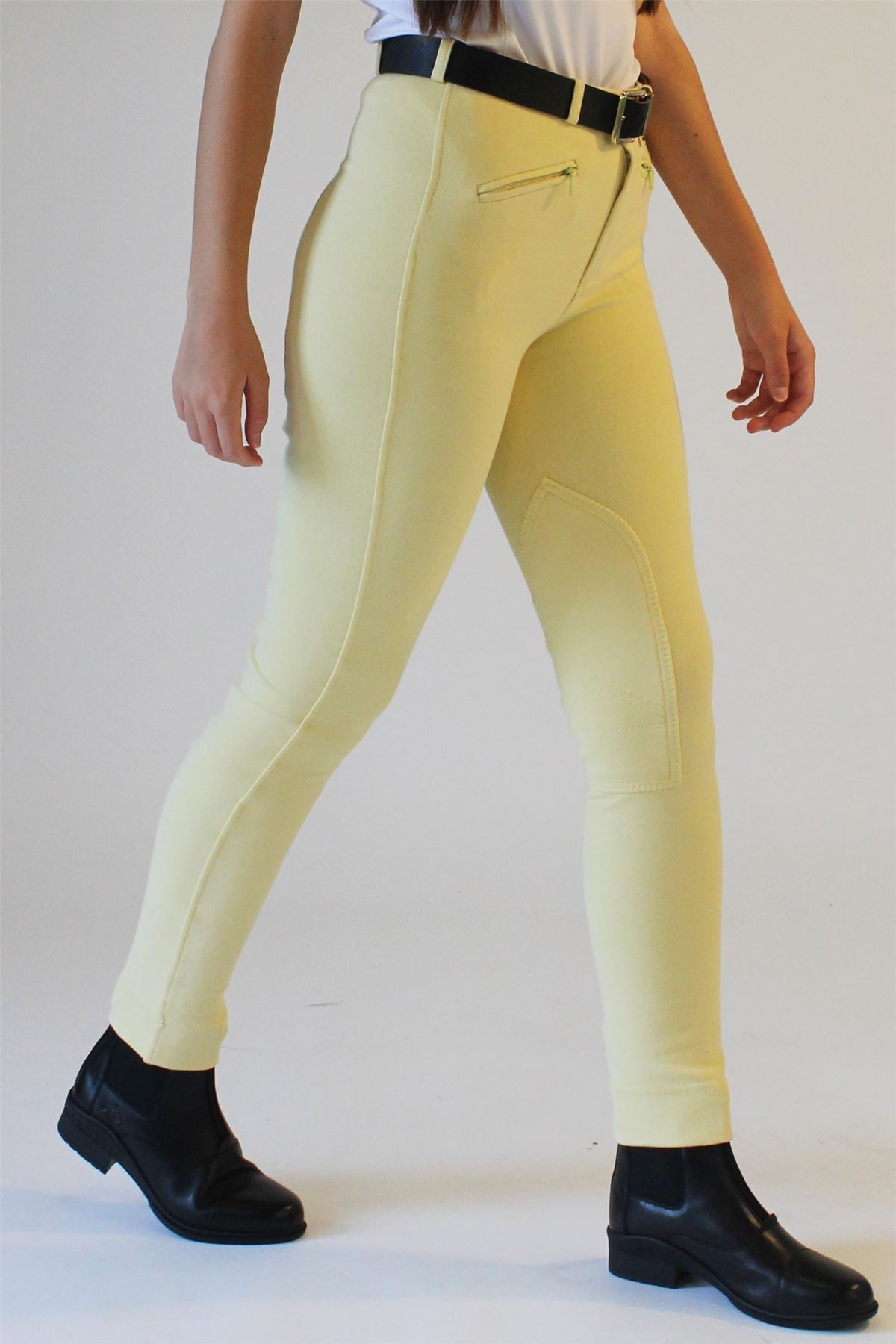 Rider wearing canary yellow jodhpurs with a black belt and short black riding boots
