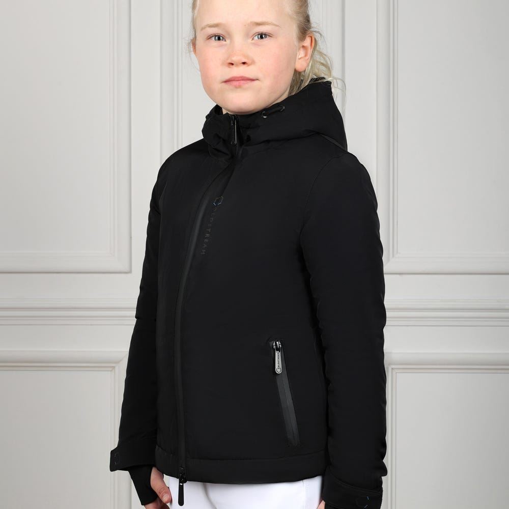Young rider wearing a black hooded waterproof riding jacket and white breeches